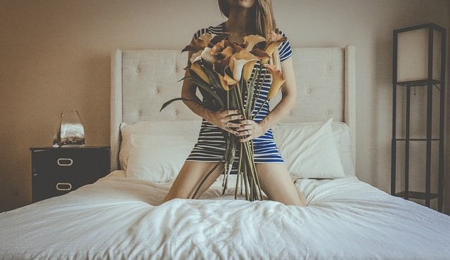 Kobieta trzyma kwiaty i klęka na łóżku